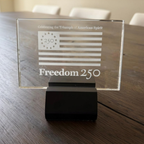 Glass plaque with 'Freedom 250' on a wooden table