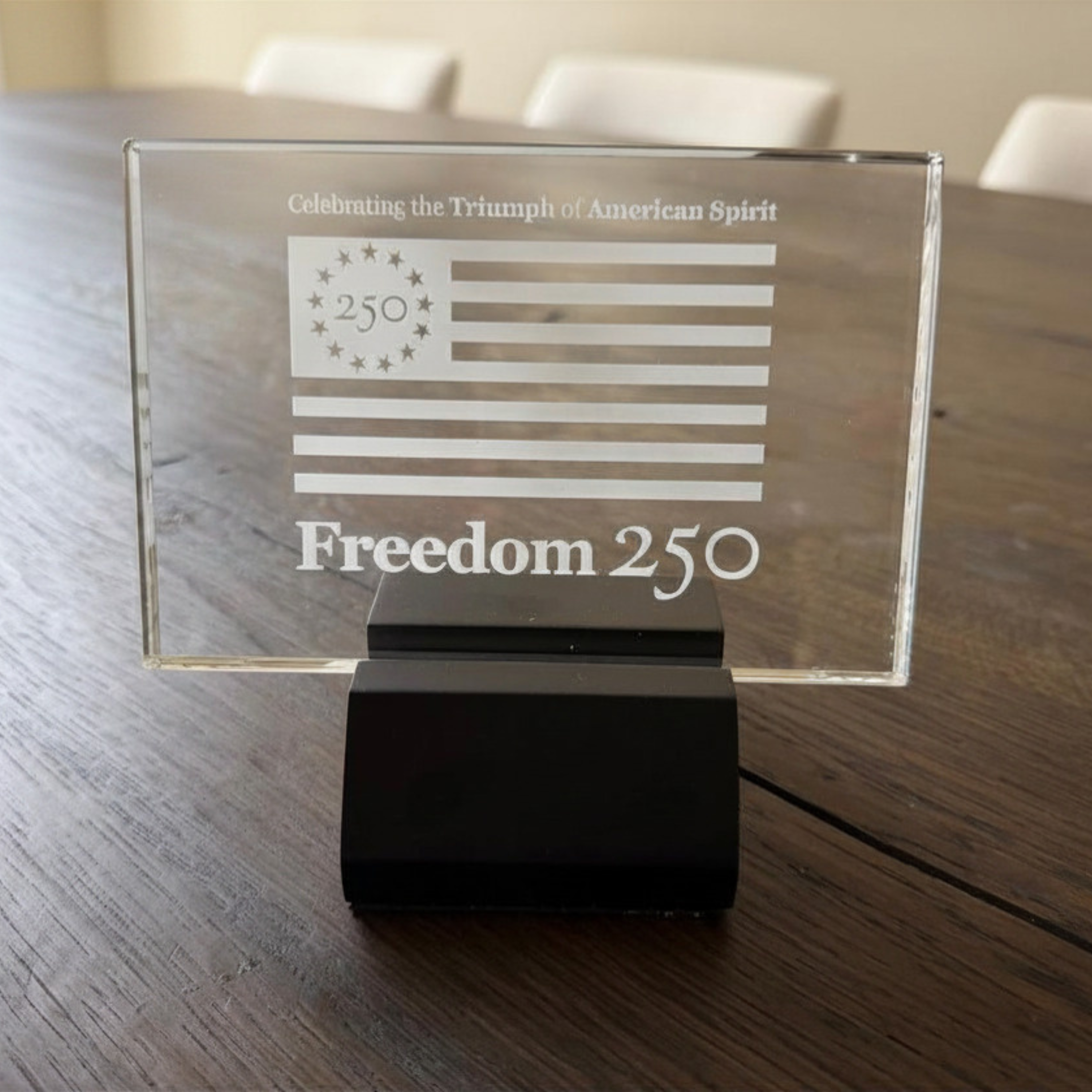 Glass plaque with 'Freedom 250' on a wooden table