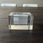 Clear glass block with engraved design on a wooden table