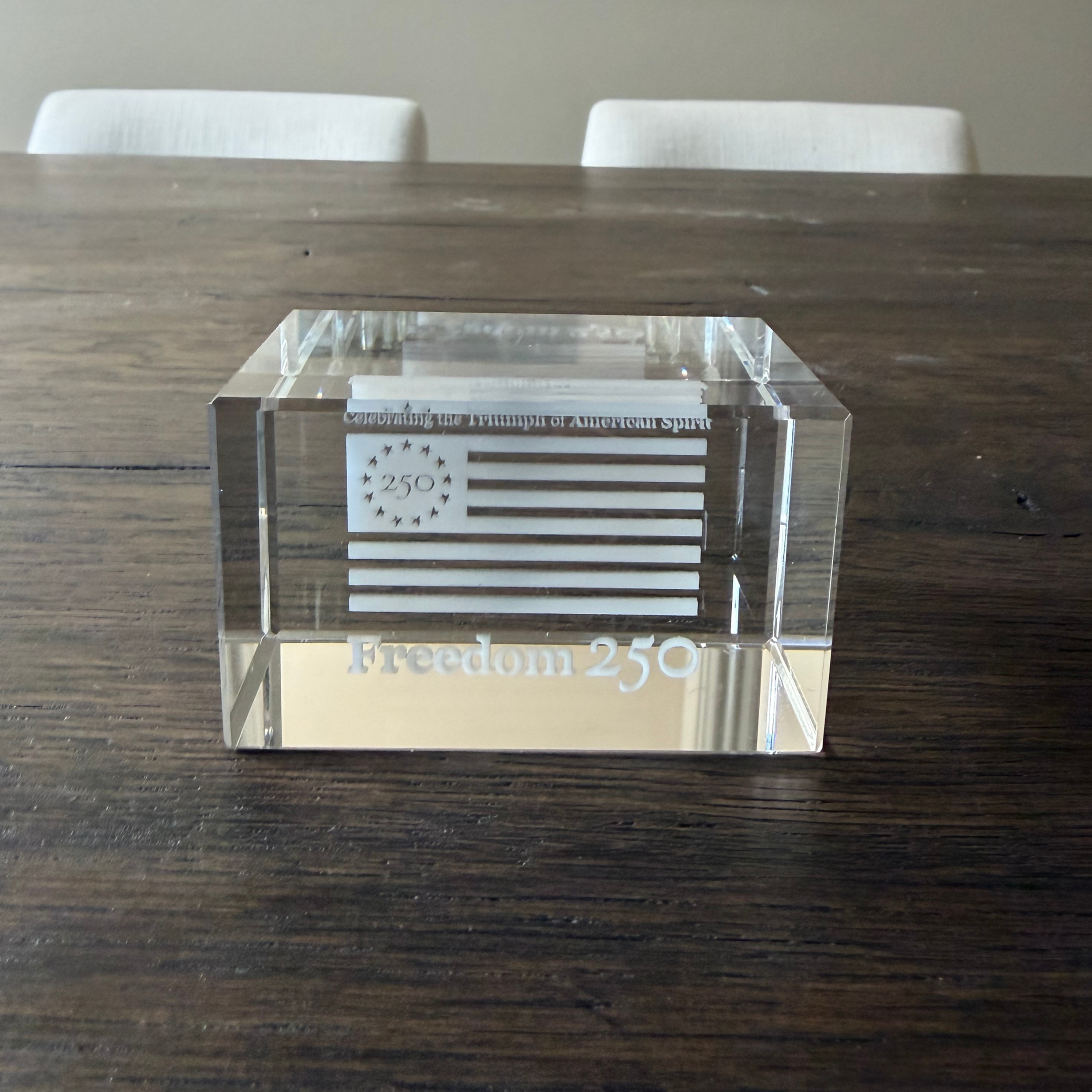 Clear glass block with engraved design on a wooden table
