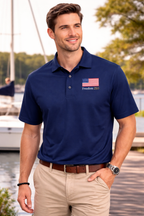 Man wearing a blue polo shirt with an American flag design by a waterfront.