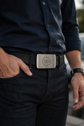 Person wearing a black belt with a silver buckle, standing outdoors.