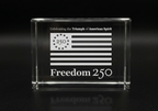 Clear glass block with engraved American flag and text on a black background