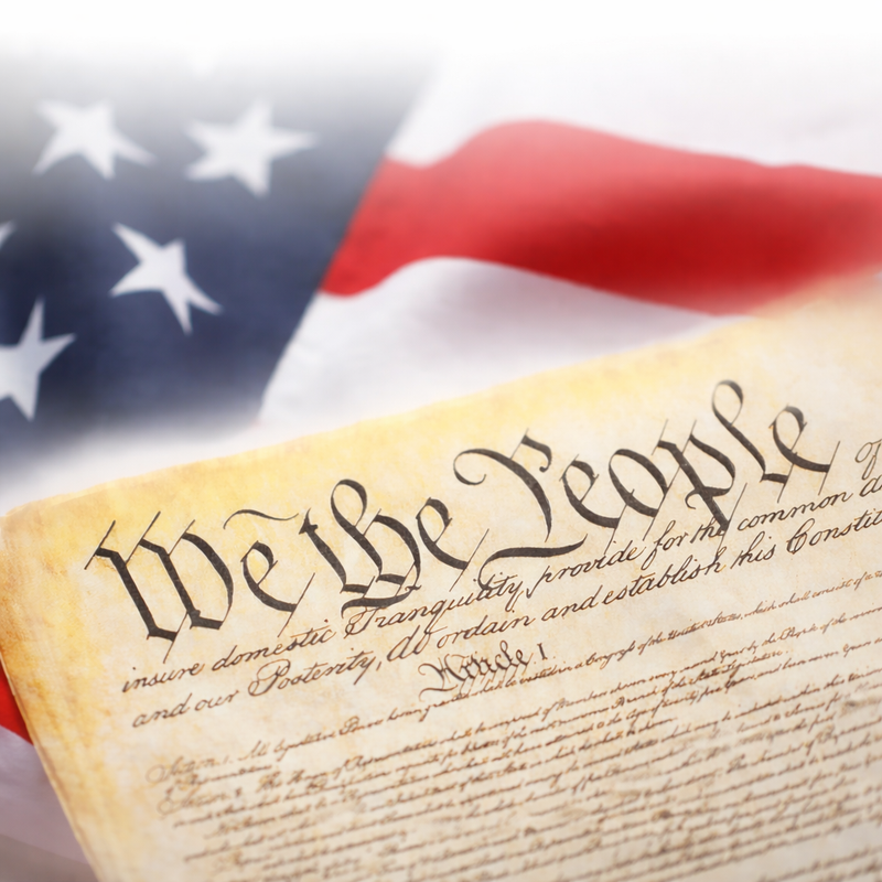 United States Constitution with American flag in the background