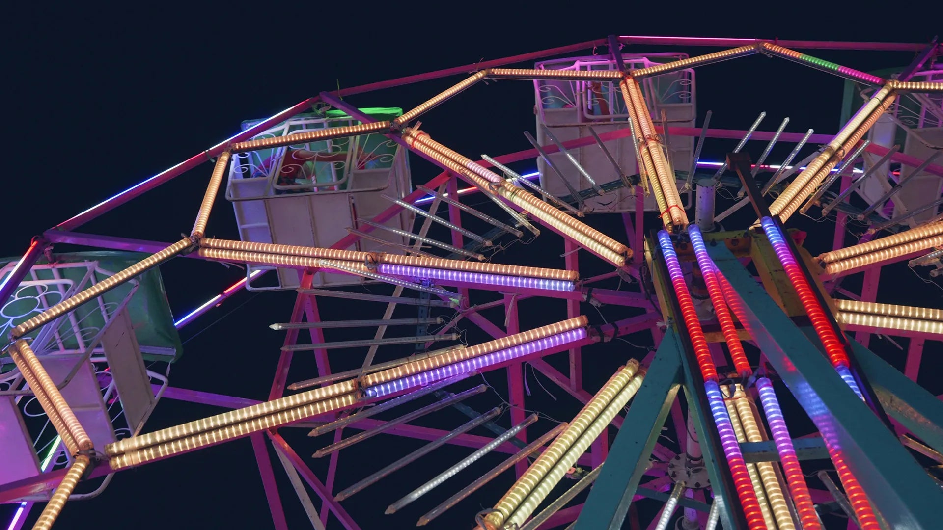 Ferris wheel at night with colorful lights against a dark sky