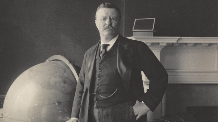 Man in formal attire standing next to a large globe in a room with a piano.